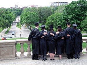 Students embracing and standing outside in their black cap and gowns.